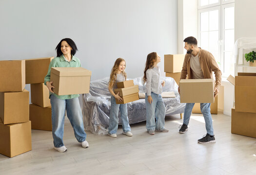 Family parents children moving boxes into home. Smiling parents and kids carry cartons in a bright room, beginning unpacking and settling into a fresh space. Clear concept of happy relocation