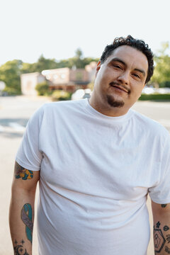 Candid portrait of a relaxed man in white t-shirt with tattoos