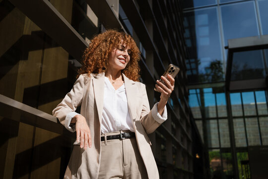 Businesswoman uses a Mobile Phone outside the Office Buildings