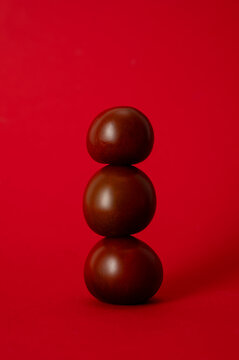Stack of three dark tomatoes on a red background
