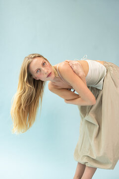 Fashion Portrait of Blonde Model Bending Forward in Cream Silk Top