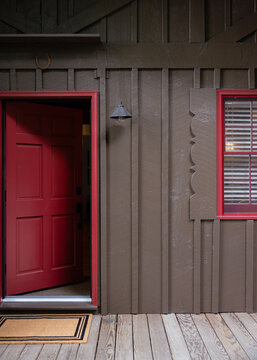 Open Red Front Door on a Dark Board-and-Batten House Exterior