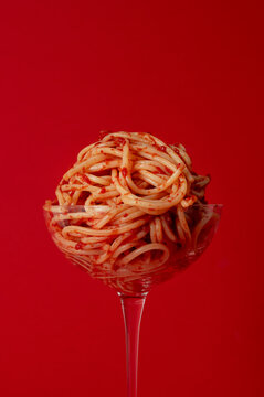 Spaghetti in a cocktail glass on a red background