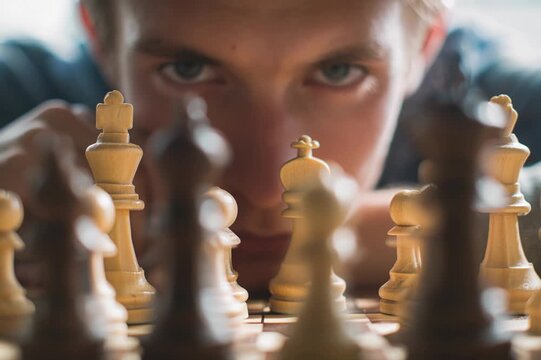 Intense young man with a focused gaze analyzing the chessboard before making his move