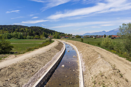 River restoration with channel cleaning and widening activity in a rural location. The landscape has trees and fields.