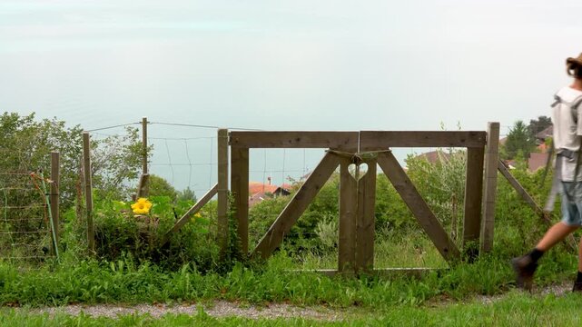 Man carries baby across rustic wooden gate in Merligen Switzerland