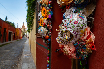 Naklejka premium A vibrant display of Day of the Dead decorations adorns a building in San Miguel de Allende, Mexico, featuring colorful sugar skulls and flowers, celebrating the lives of deceased loved ones.