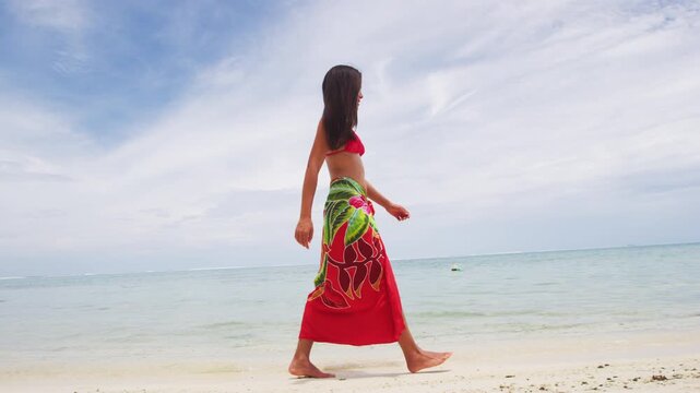 Vacation travel woman relaxing on paradise beach with palm trees on holidays. Girl on beach in pareo and bikini on Tahiti, French Polynesia. Vertical video of real woman model without any makeup