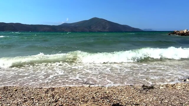 Sea Waves Crashing On Pebble Beach Shore With Mountain Landscape 