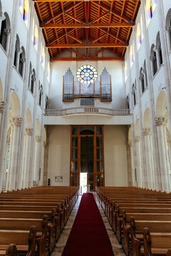 Pristina, Kosovo - 19 June 2025: View of the interior of the Cathedral of Saint Mother Teresa featuring wooden pews, a red carpet aisle, and a pipe organ under a circular stained glass window.
