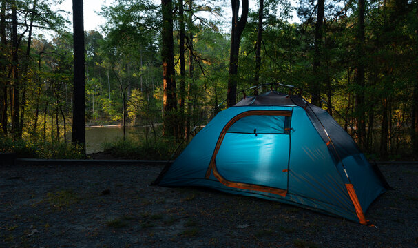 Sun rising over the lake behind a blue tent