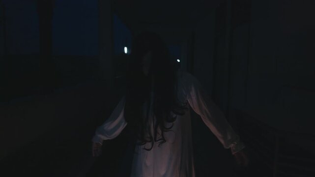 Scary halloween ghost figure with long black hair emerges from night, wearing white costume, dead spirit haunting dark shadows, creating eerie scene for frightful day.