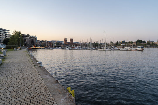 Oslo, Norway - 23 July 2025: View of Oslo City Hall and the marina with boats moored along the waterfront at sunset.