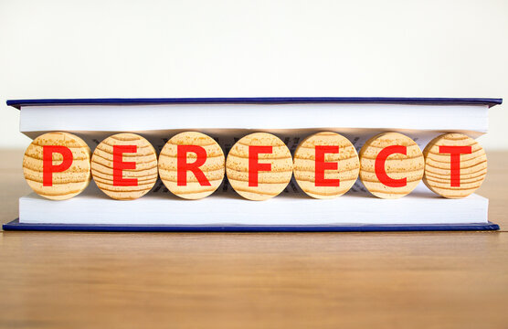 Perfect word symbol. Concept word Perfect on beautiful wooden circles in book. Beautiful wooden table white background. Business perfect word concept. Copy space.