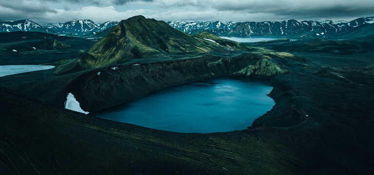 Panoramic view of Lj&oacute;tipollur crater lake in Iceland's Highlands, surrounded by dark volcanic slopes beneath dramatic storm clouds. A remote and breathtaking volcanic landscape.