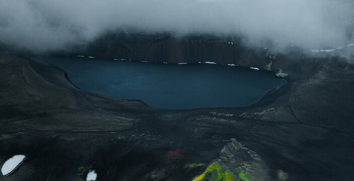 Panoramic view of Lj&oacute;tipollur crater lake in Iceland's Highlands, surrounded by dark volcanic slopes beneath dramatic storm clouds. A remote and breathtaking volcanic landscape.