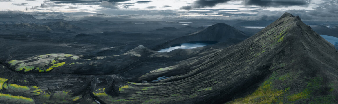 Panoramic view of Lj&oacute;tipollur crater lake in Iceland's Highlands, surrounded by dark volcanic slopes beneath dramatic storm clouds. A remote and breathtaking volcanic landscape.