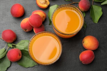 Apricot juice in glasses, fresh fruits and leaves on black table, flat lay © New Africa