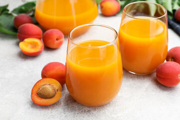 Apricot juice, fresh fruits and leaves on light table, closeup © New Africa