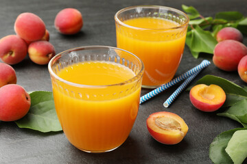 Apricot juice in glasses, fresh fruits and drinking straws on black table, closeup © New Africa