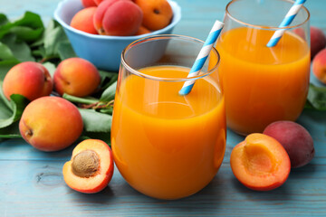 Apricot juice in glasses, fresh fruits and leaves on light blue wooden table, closeup © New Africa