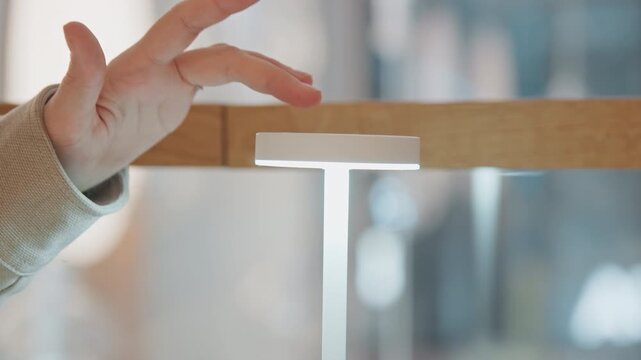 Close up of hand interacting with and activating touch sensitive white LED light fixtures transitioning from off to on state. interaction involves gentle swiping gestures over top surface