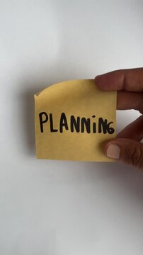 Hand holding planning sticky note on white background close up