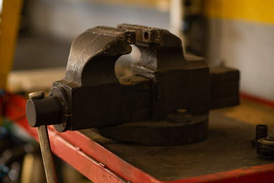 Metal bench vise clamped tightly on workbench in workshop.