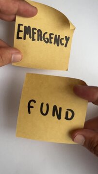 Hand holding sticky notes with emergency fund text on white background