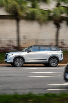 Side Profile View of Silver Jaecoo J7 SUV Driving on Urban City Street with Motion Blur
