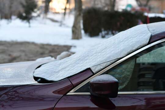 Winter windshield cover protecting parked car from frost and ice on cold morning