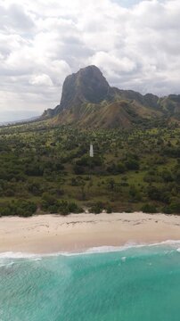 Aerial view of Nuca Molas peak rising above lush green hills and tropical vegetation in Satar Mese Barat, East Nusa Tenggara, Indonesia.