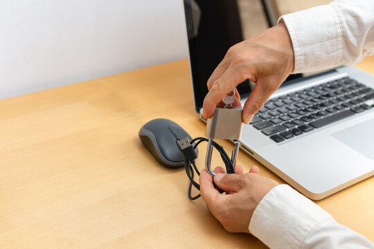 Rear view of man securing computer mouse cable with padlock