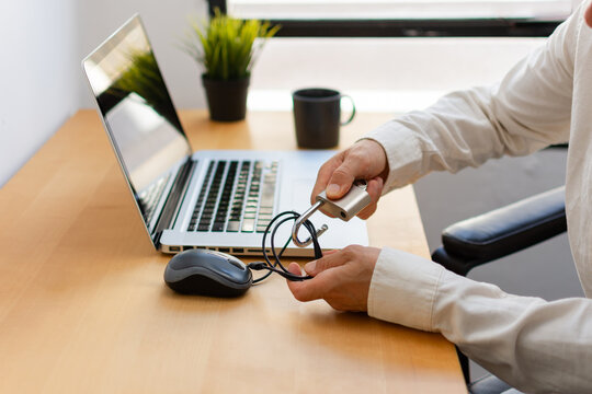 Close up of man securing computer mouse cable with padlock