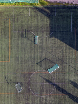 Aerial view of Virpiniemi Sport soccer field with green artificial turf, white markings, and goal posts casting long shadows in Oulu, North Ostrobothnia, Finland.