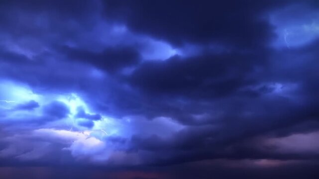 Lightning flashes through dark storm clouds above a distant horizon at dusk