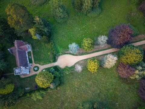 Area of view looking directly down on Saint Stevens Church in Pamphill Dorset showing the 1908 built Church set in beautiful Parkland with colourful trees and a gravel path 