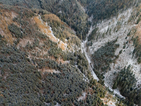 Aerial view of the historic copper mine dumps in Svatodusna dolina, featuring snow-dusted evergreen forests and a winding valley path in Lubietova, Banska Bystrica Region, Slovakia.