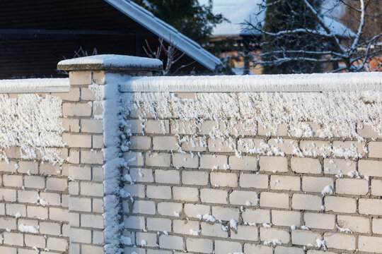 Frost clings to a snowy brick wall