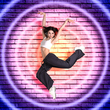Young hip-hop dancer jumping against brick wall with colorful circles. Bright creative poster