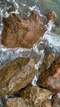 Vertical video. Periodic surge of water among coastal rocks due to a meteorological tsunami. Speed ​​0.9x. Mallorca, Spain.