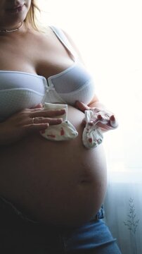 Pregnant Belly with Tiny Baby Socks, Expecting a Newborn, Pregnancy Announcement, Motherhood and Baby on the Way