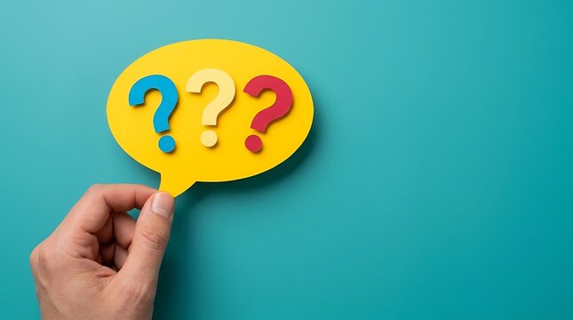 Hand holding yellow speech bubble with red blue yellow question marks, symbolizing confusion or inquiries for communication or problem solving concept.