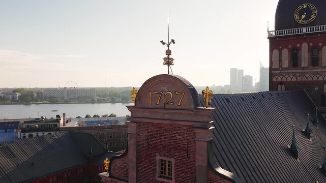 An aerial close up view of Riga Cathedral roof ornaments and tower in Old Riga, Latvia, with the Daugava River under morning sunlight.