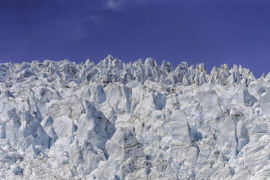 Aerial view of the jagged ice formations of the Matanuska Glacier, showcasing deep blue crevasses and sharp ice pinnacles under a clear sky in Glacier View, Alaska, United States.
