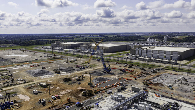 Aerial view of data center construction expansion with heavy machinery and earthworks, adjacent to an existing facility in Clarksville, Tennessee, United States.