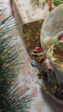 Animation of snow falling over christmas snow globe and decorations