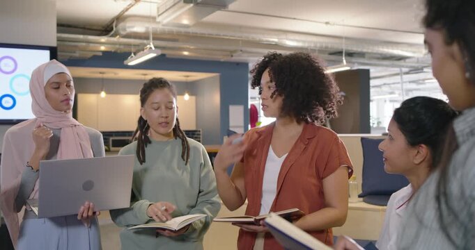 Diverse coworkers listening, responding to offscreen cue, aligning plan in office with laptops