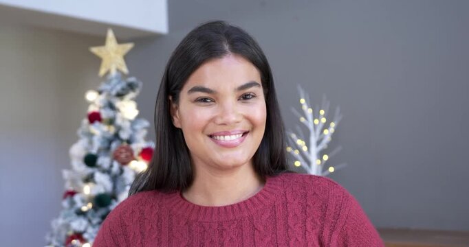 African American woman on cue facing camera, smiling laughing at home by Christmas tree