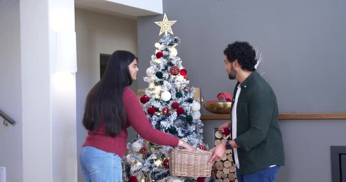 African American couple preparing for holiday, decorating flocked tree at home using woven basket